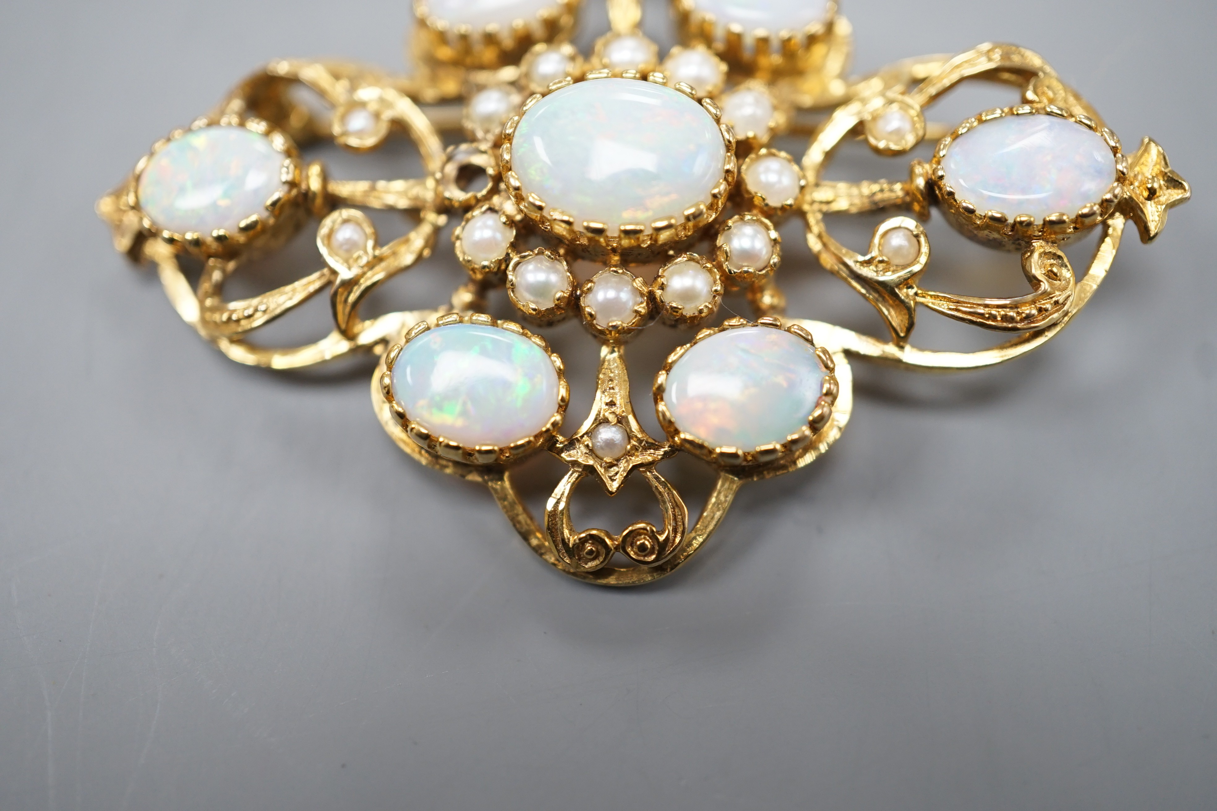 An early 1970's 9ct gold, graduated oval white opal and split pearl set brooch, of quatrefoil shape (pearl missing), 48mm, gross weight 9.3 grams.